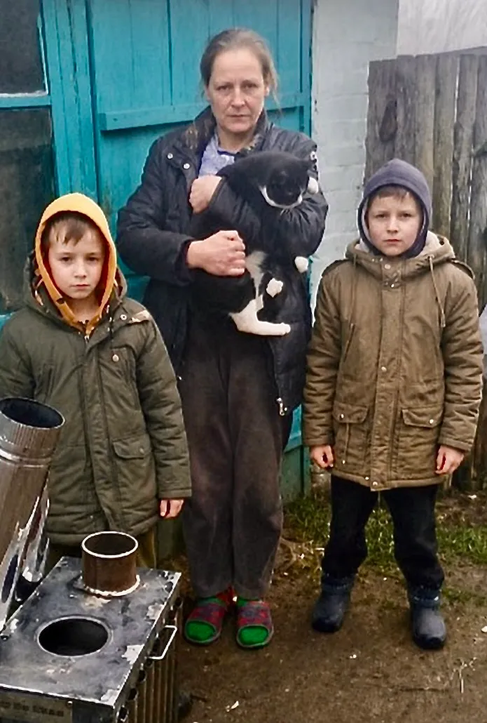 A Ukrainian mother with her children, cat, and wood-burning stove